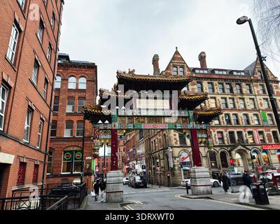 Manchester, UK - January 29, 2026: Vibrant Chinatown gate in Manchester frames brick buildings and pedestrians on a busy urban street. Stock Photo