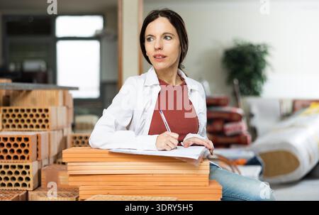 Interested brunette making notes while planning home renovation Stock Photo