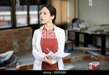 Interested brunette making notes while planning home renovation Stock Photo