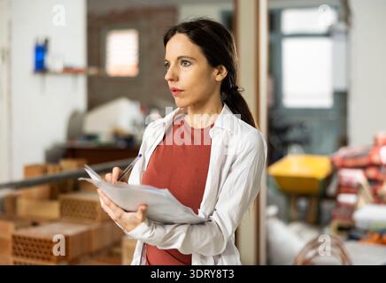 Interested brunette making notes while planning home renovation Stock Photo