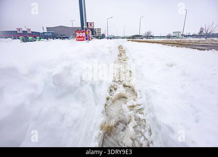 Low angle view of a narrow path cleared through deep snow leading towards a Kaufland supermarket after a heavy winter Stock Photo