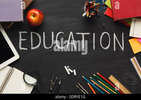 Collection of School Items Arranged on a Chalkboard With Word Education Written in Chalk Stock Photo