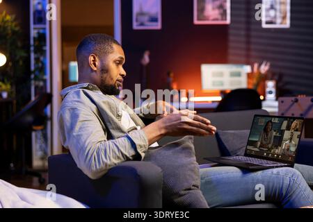 Smiling african american man hosting a virtual family meeting online via video conference, meeting with the relatives and sharing latest news. Guy uses web connection to chat with loved ones. Stock Photo