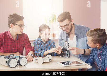 Students Learn Robotics Skills With Teacher During a Technology Class in a Bright Classroom Stock Photo