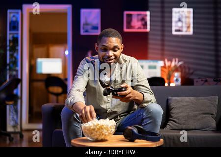 Young guy having fun with video games on television modern setup, connecting his console on smart tv in living room and enjoying chill game night at home. African american gamer playing tournament. Stock Photo