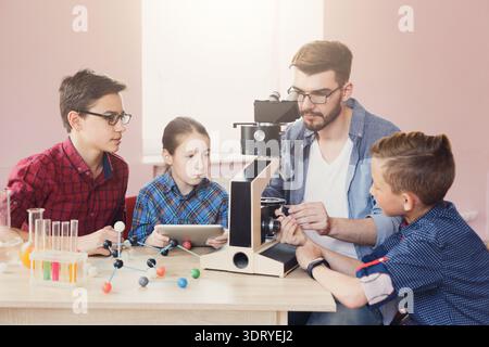 Students Learn About Science With a Teacher Using a Microscope During a Class Activity Stock Photo