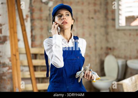 Woman foreman talking on a mobile phone inside building under construction Stock Photo
