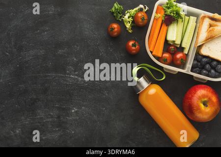 Healthy Lunch Box and Fresh Fruits Combined in a Colorful Collage on a Dark Background Stock Photo