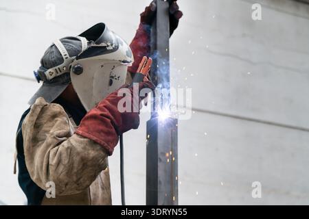 Welder performing arc welding while wearing safety gloves and a protective helmet Stock Photo