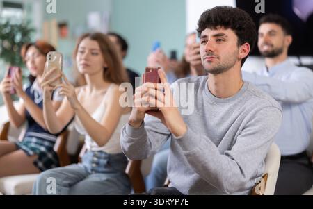 Young guy using mobile phone to scan QR code during interactive lesson Stock Photo