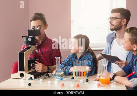 Students Learn About Science and Have Fun Using a Microscope in a Classroom During the Afternoon Stock Photo