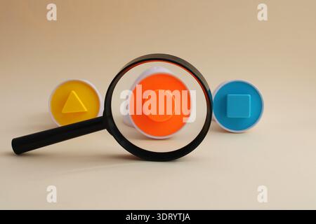 Magnifying glass finds a circle among several geometric shapes Stock Photo