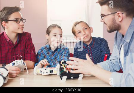 Group of Students Learn About Robotics From Teacher in Classroom During Afternoon Session Stock Photo