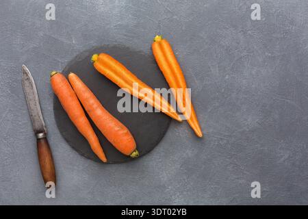 Fresh Carrots and Knife on Dark Surface Ready for Preparation in Kitchen Setting Stock Photo