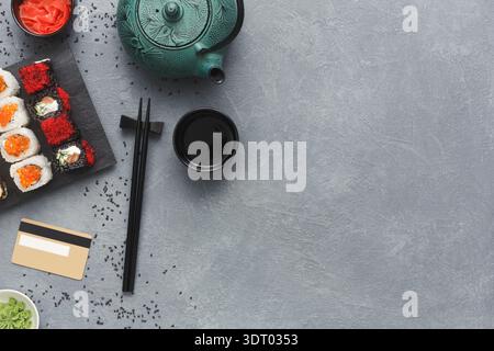 Sushi and Tea Set on Gray Surface With Chopsticks, Wasabi, and Card Ready for a Meal Stock Photo