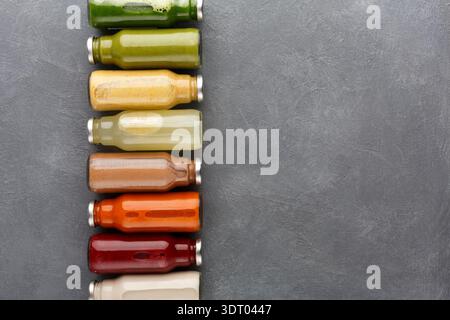 Different Flavors of Cold Pressed Juice in Glass Bottles on a Grey Surface Stock Photo