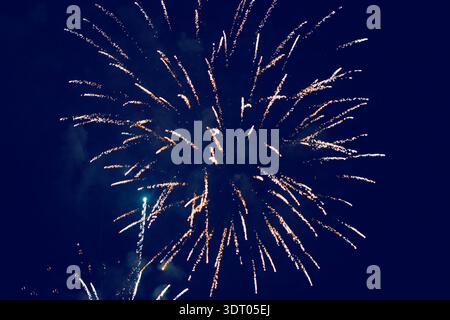 Golden fireworks burst brilliantly against a deep night sky, illuminating the darkness with sparkling trails of light. Vibrant display captures excite Stock Photo