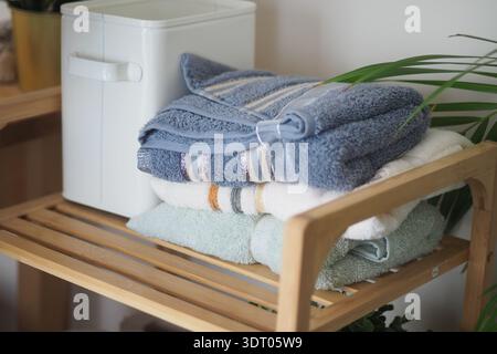 Towels stacked on wooden shelf in quiet indoor space Stock Photo
