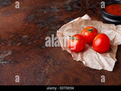 Fresh Tomatoes on Brown Paper With Sauce in a Black Bowl on a Rustic Table Stock Photo