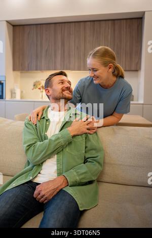 Happy cheerful couple of man and woman enjoying spending time together in cozy living room at home. Stock Photo