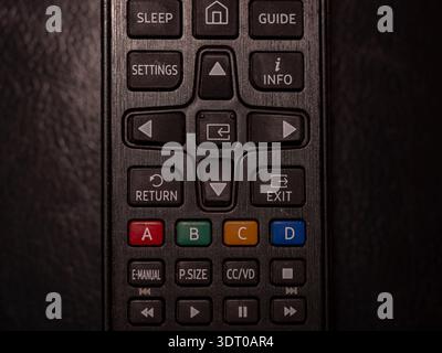 Close-up of television remote control buttons showing navigation, color, and settings keys under low lighting Stock Photo