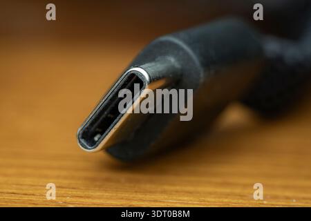 Macro close-up of a USB-C cable connector resting on a wooden surface, illustrating technology and connectivity Stock Photo