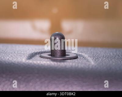 Close-up macro of a black car door lock pin on textured interior surface, symbolizing security, protection, and design detail Stock Photo