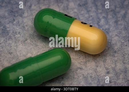 Close-up of yellow and green capsules on a textured background, representing medicine, pharmaceuticals, and healthcare treatment Stock Photo