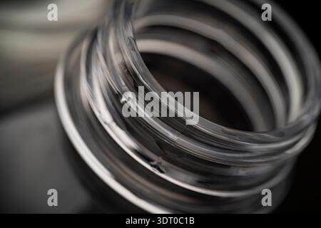 Macro close-up of a clear plastic or glass bottle neck showing spiral thread details and reflections in soft focus Stock Photo