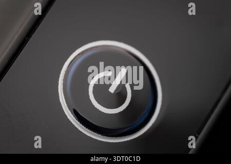 Macro close-up of a white power button symbol on a glossy black surface, representing technology, control, and modern design Stock Photo