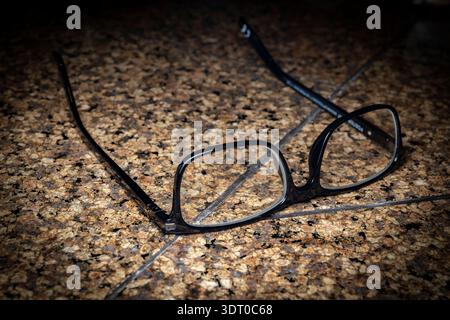 Black eyeglass frames lying on a granite countertop, symbolizing vision, focus, and everyday lifestyle moments Stock Photo