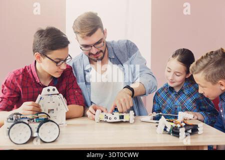 Kids Learn Robotics With a Teacher While Building Projects in a Classroom Setting Stock Photo