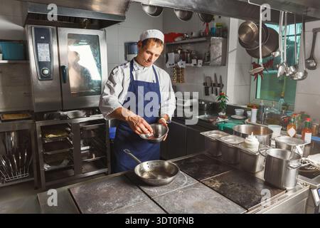 Chef Prepares Ingredients in a Commercial Kitchen With Various Utensils and Equipment Stock Photo