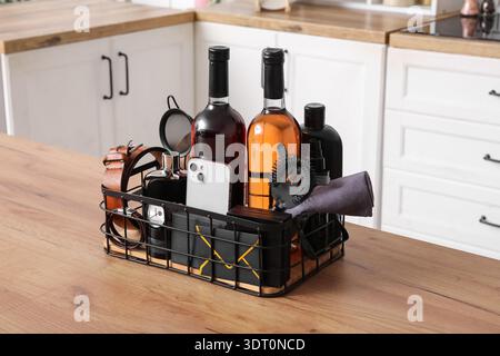 Gift basket with male accessories, bottles of wine and mobile phone on wooden table in kitchen Stock Photo