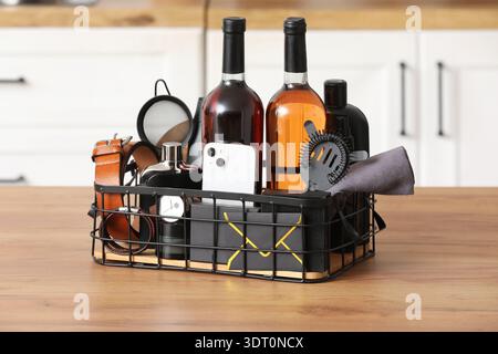 Gift basket with male accessories, bottles of wine and mobile phone on wooden table in kitchen Stock Photo