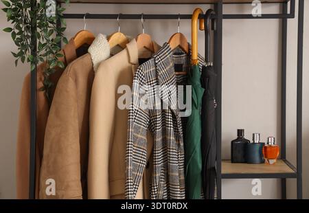 Rack with coats, umbrellas and perfume bottles in room Stock Photo