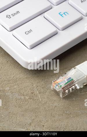Close-up of a keyboard and an ethernet cable connection on a concrete surface Stock Photo