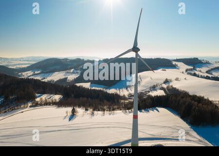 Wind turbine in an open snowy field during winter. Concept of clean energy future and sustainable power. Stock Photo