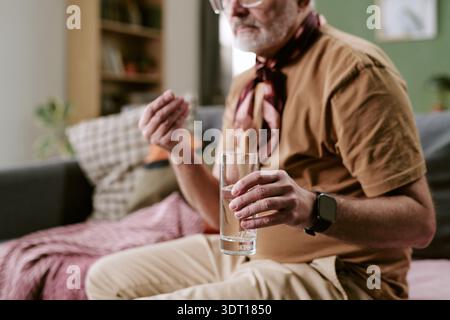 Senior Caucasian Man Taking Medication While Sitting Indoors on Sofa Stock Photo