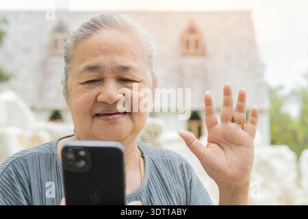 Elderly Asian woman enjoy and fun active outdoor lifestyle using smartphone taking selfie with friend at outside of the museum Stock Photo