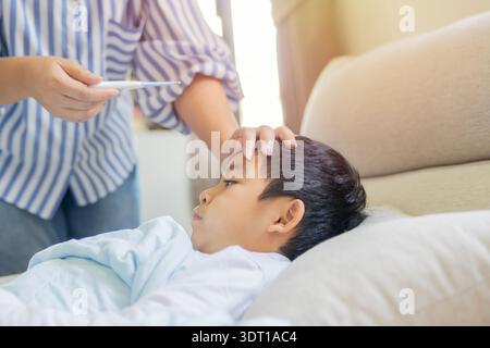 Mom, sick boy and tool for fever in home, virus and monitor temperature for covid infection. Mother, son and childcare for cold or flu at home, thermo Stock Photo