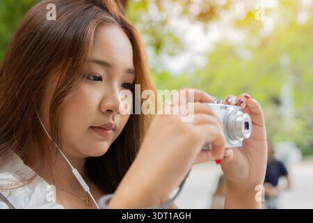Side view cloes-up of Asian woman using digital camera, taking picture during her vacation. Lifestyle, travel, people concept. Stock Photo