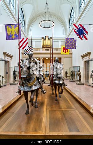 Visitors explore the Middle Ages main hall at the Metropolitan Museum of Art in Manhattan. The hall features knights on horseback and various flags. Stock Photo
