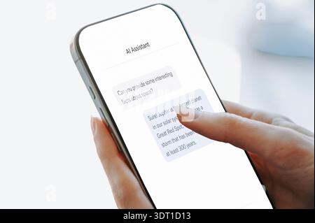 Close-up of a woman interacting with a smartphone displaying a modern AI assistant chat interface. Minimal clean design with chat bubbles highlights a Stock Photo