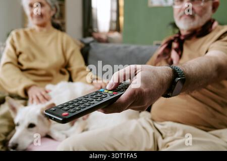 Senior Caucasian Man Holding Remote Control Sitting with Senior Caucasian Woman Stock Photo