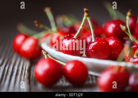 Ripe cherries arranged in ceramic dish on wooden surface. Fresh glossy red fruits, natural light, organic harvest Stock Photo