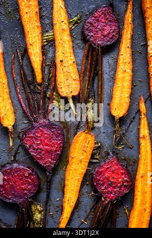 Roasted beetroot and carrots with spices on dark background. Baked vegetable food with rich texture Stock Photo