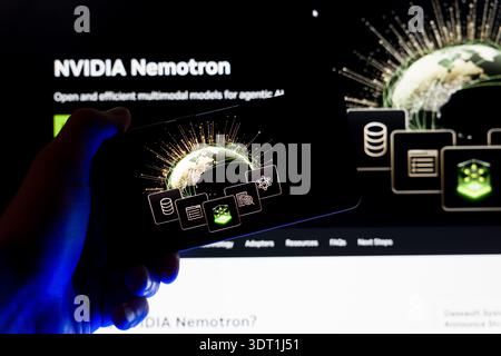 Hand holding smartphone displaying NVIDIA Nemotron graphic on screen with blurred website background, concept for multimodal artificial intelligence a Stock Photo