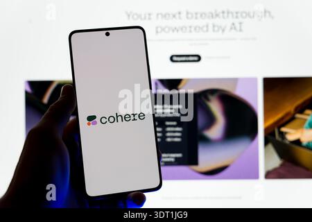 Hand holding a smartphone displaying the Cohere AI logo on the screen with the company website in the background, concept for enterprise artificial in Stock Photo
