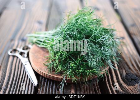 Bunch of fresh dill greens on wooden cutting board on rustic table. Organic culinary herbs background Stock Photo
